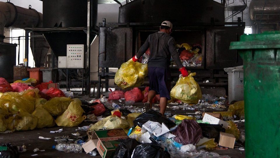 A Medical Waste Management Unit worker navigates the waste-strewn warehouse floor of the Dangkor landfill in Phnom Penh on April 9, 2020.