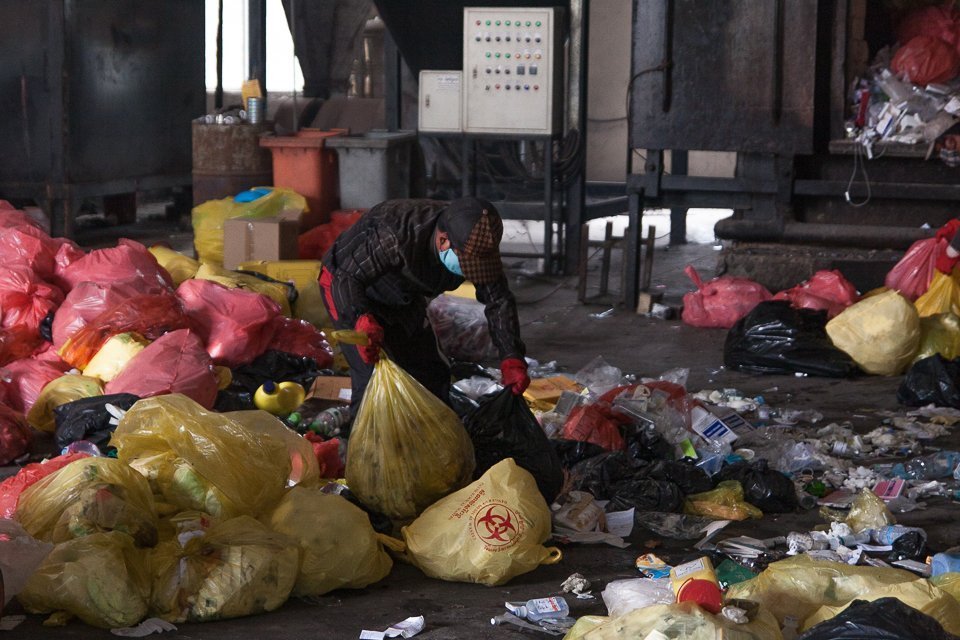 Nguon Sokheng lifts bags of medical waste to be incinerated at the Dangkor landfill in Phnom Penh on April 9, 2020. Gerald Flynn