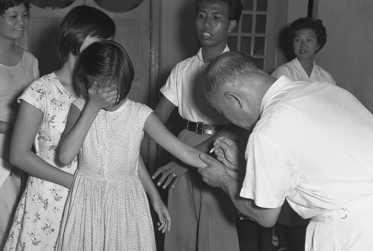 A girl covering her face as she is being vaccinated for smallpox on 16 April 1959.