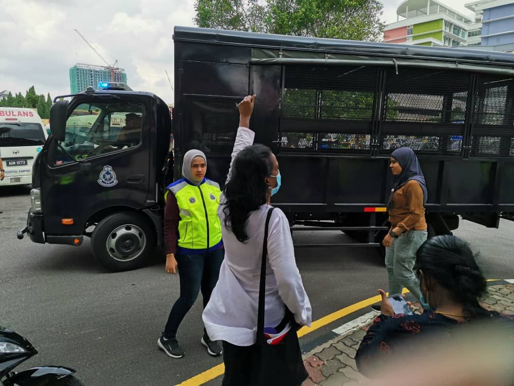 Polis menahan Saras (berbaju putih) dan penunjuk perasaan lain di luar Hospital Ipoh pada 2hb Jun 2020.
