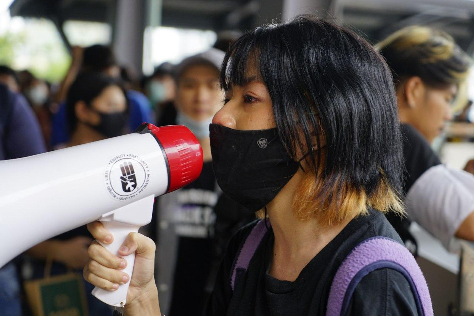 A protestor uses a megaphone during a flash mob at Lad Phrao intersection in Bangkok on 17 October 2020.