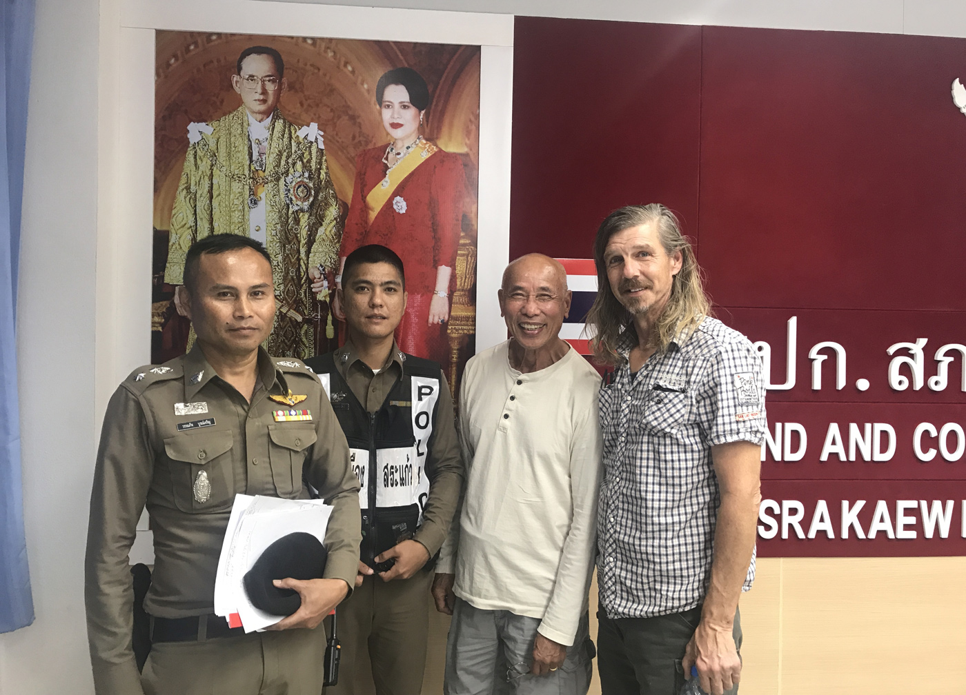 Cambodian-American CNRP supporter Hay Kimsan (second right) and American Daniel Capka pose with Thai police officers at Sa Kaeo police station on 8 November 2019.