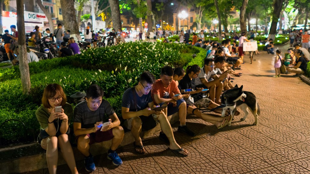 Teenagers use smartphones in a Hanoi park in 2016. (Vietnam Stock Images/Shutterstock)
