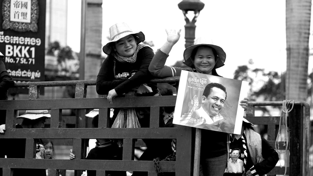 Two women hold up a photo of Kem Ley at his funeral.
