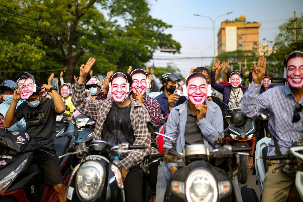Protesters in Mandalay, Myanmar, raise the anti-coup three-finger salute while holding up Dr. Sasa face masks on 22 May 2021.