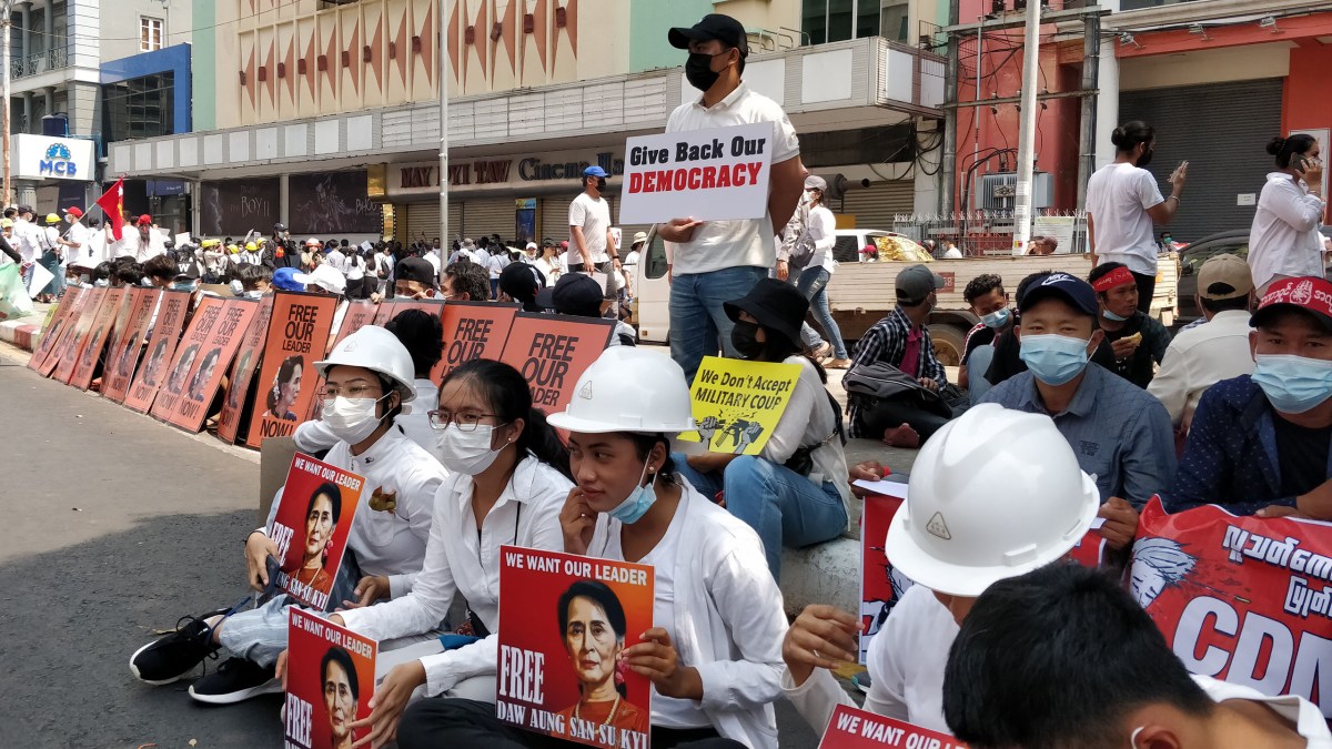 Anti-coup protesters hold placards, many depicting detained opposition leader Aung San Suu Kyi, on a Yangon street in February 2021.