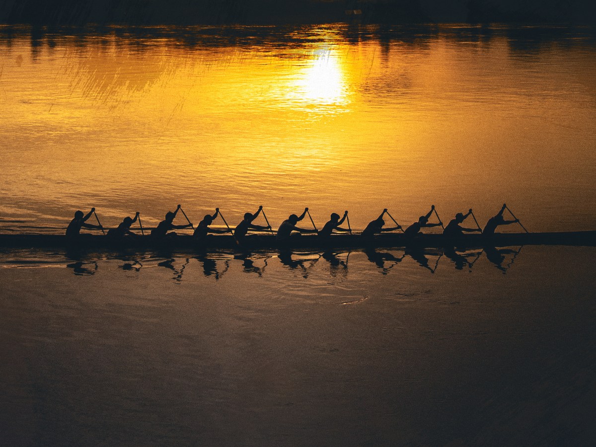 A team rowing a boat in the sunset